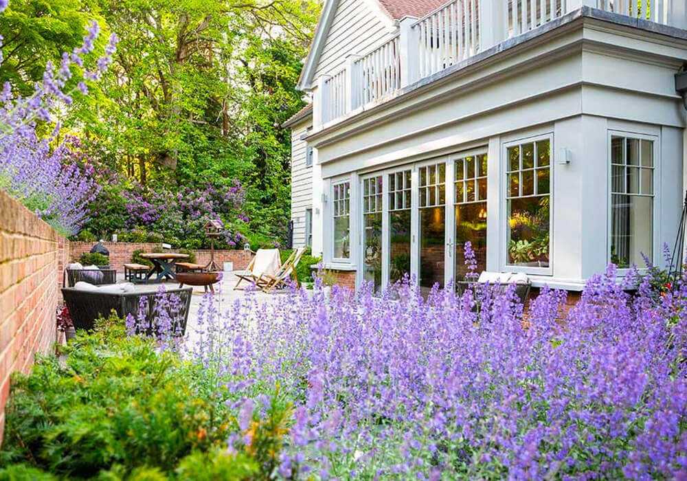 View of bifold doors and flush casement window from flowery corner of the garden