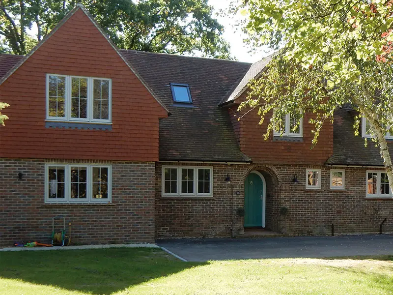 Traditional house with white timber flush casement windows with a green entrance door