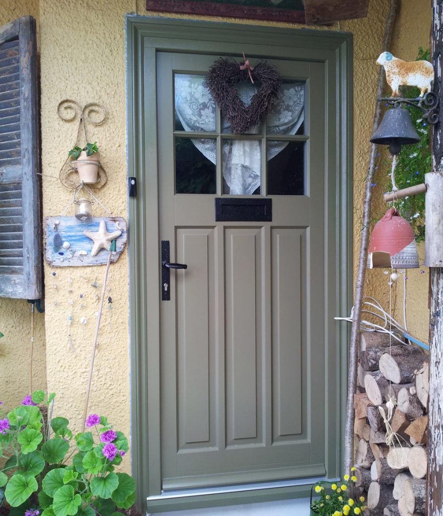 A verdant front door adorned with a decorative wreath.