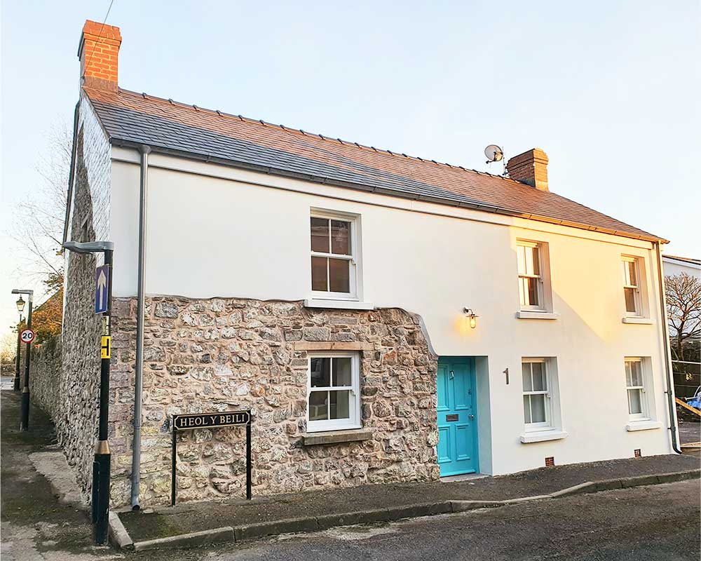 A pristine white house, adorned with a vibrant blue door and matching windows, stands out with its simple yet captivating charm.