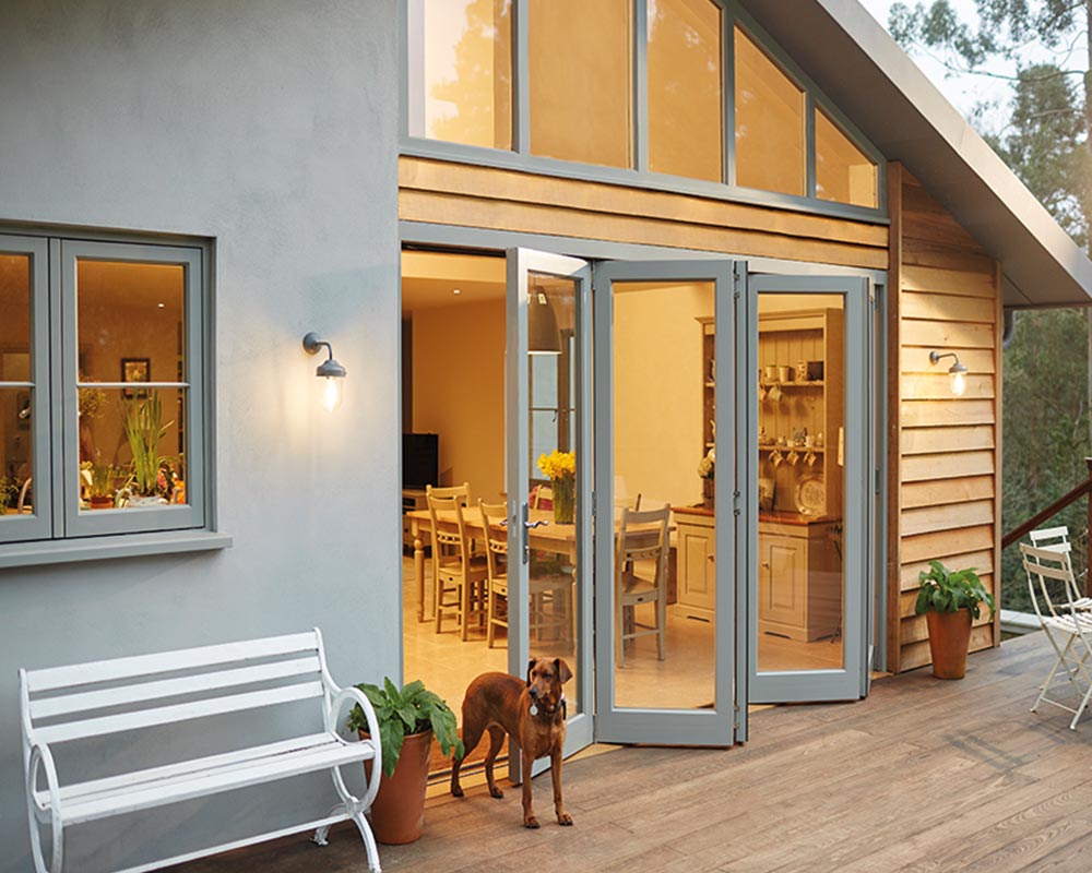 Grey bifold doors on a building with a dog in front