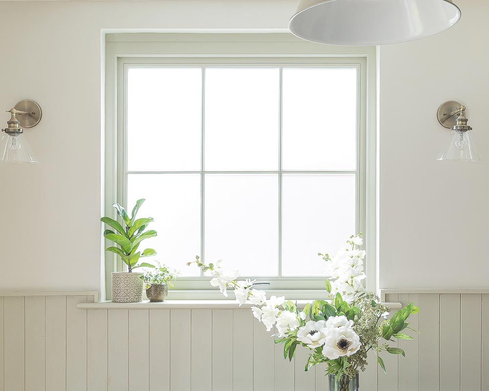 A vase brimming with vibrant flowers rests gracefully upon a table, positioned directly in front of a window.