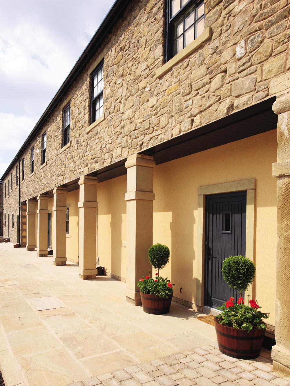 Exterior image of a house with columns that has a dark grey timber front door